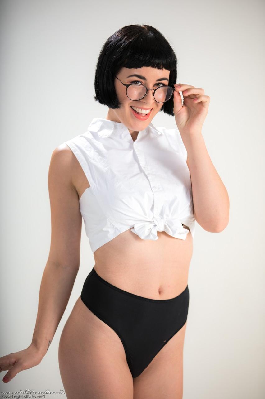 15P Dark haired chick Olive Glass removes glasses before standing naked