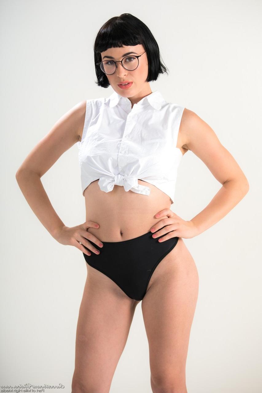 15P Dark haired chick Olive Glass removes glasses before standing naked