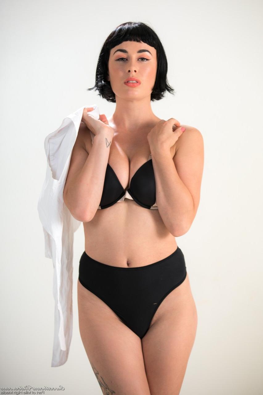 15P Dark haired chick Olive Glass removes glasses before standing naked