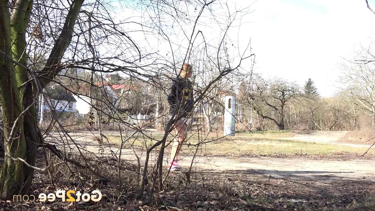 15P Chrissy Fox, une petite fille prise, pisse au milieu de buissons clairsemés.
