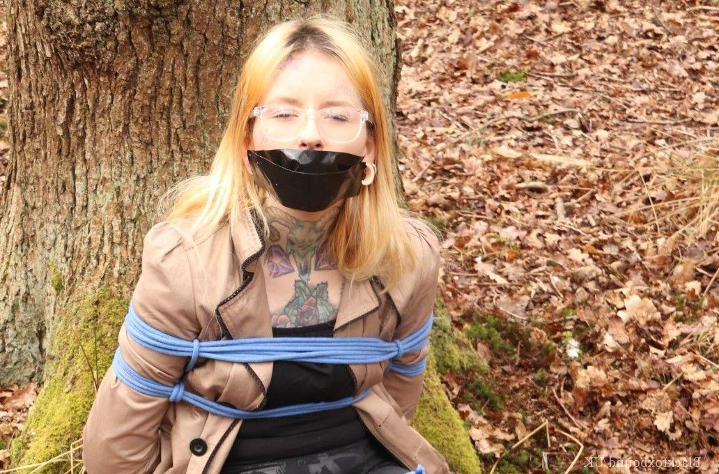 16P Nerdy girl is left gagged and rope bound against a tree in the forest