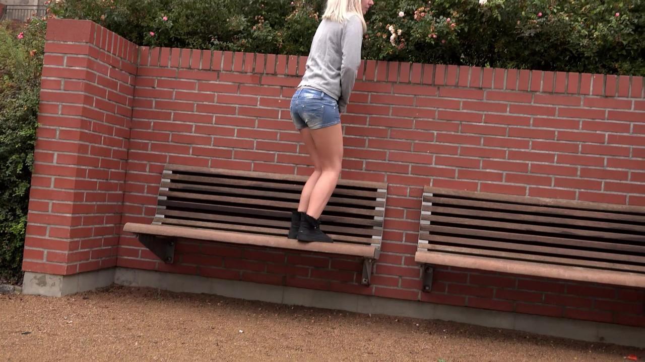 15P La blonde Debora enlève son short en jean pour faire pipi sur un banc public.