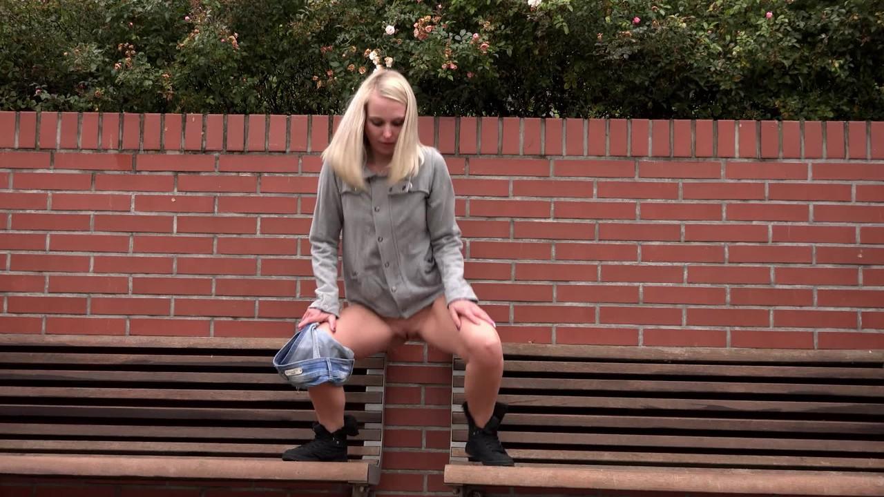 15P La blonde Debora enlève son short en jean pour faire pipi sur un banc public.