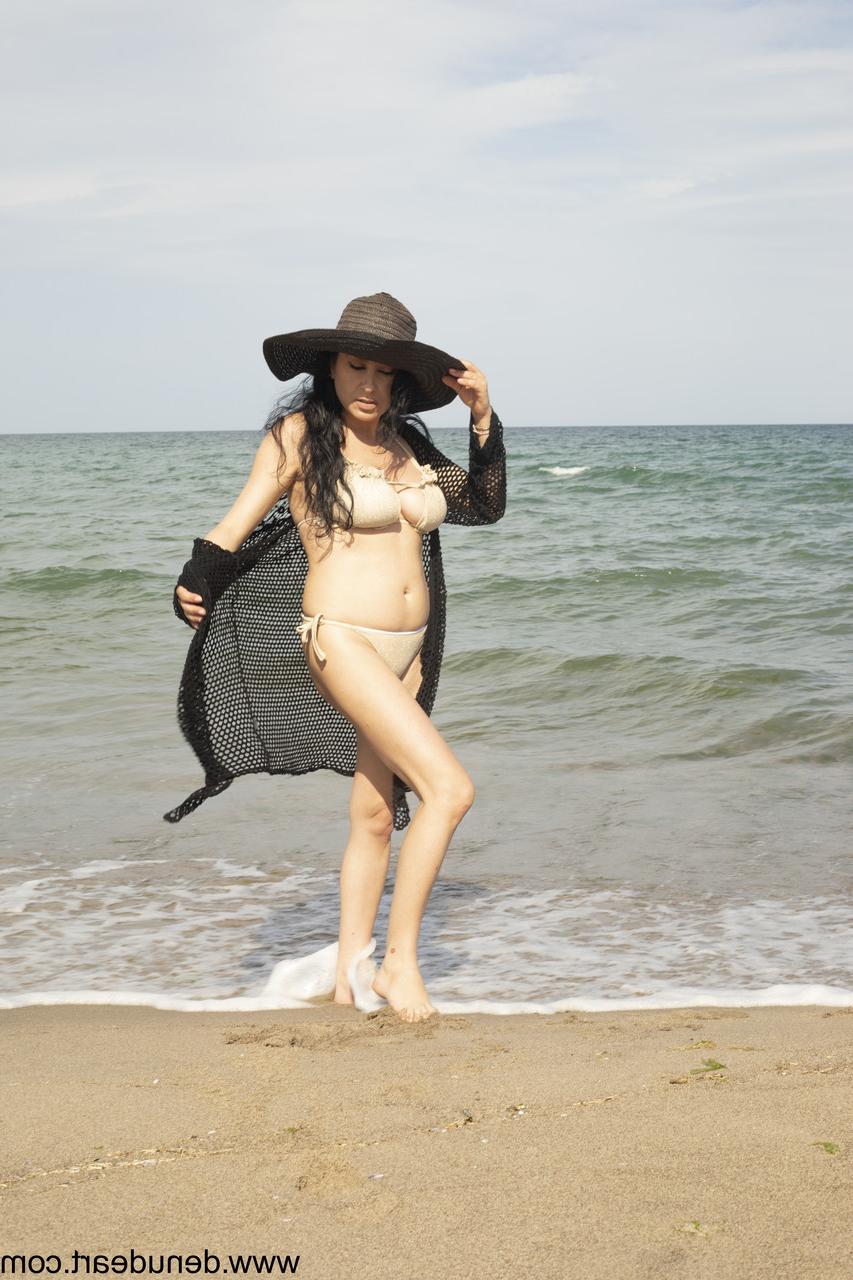 15P Dark-haired MILF poses on the beach and reveals her big juicy tits