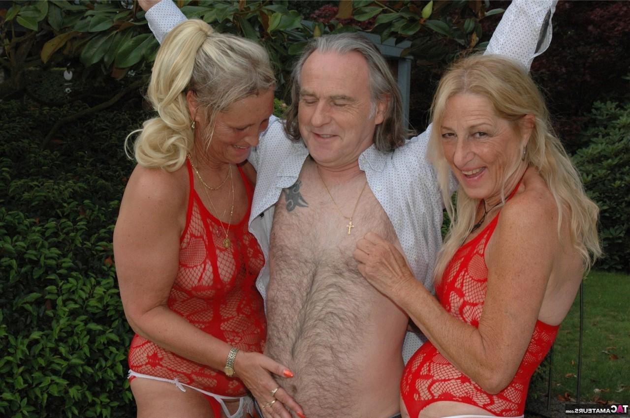 16P Two older blondes in red lingerie smoke while teasing an old man in a garden