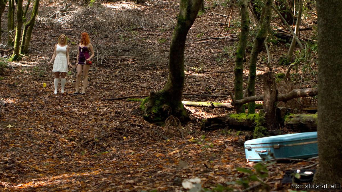 15P Une dominatrice rousse soumet la fille blonde Dee Williams à un aiguillon pour le bétail dans les bois.