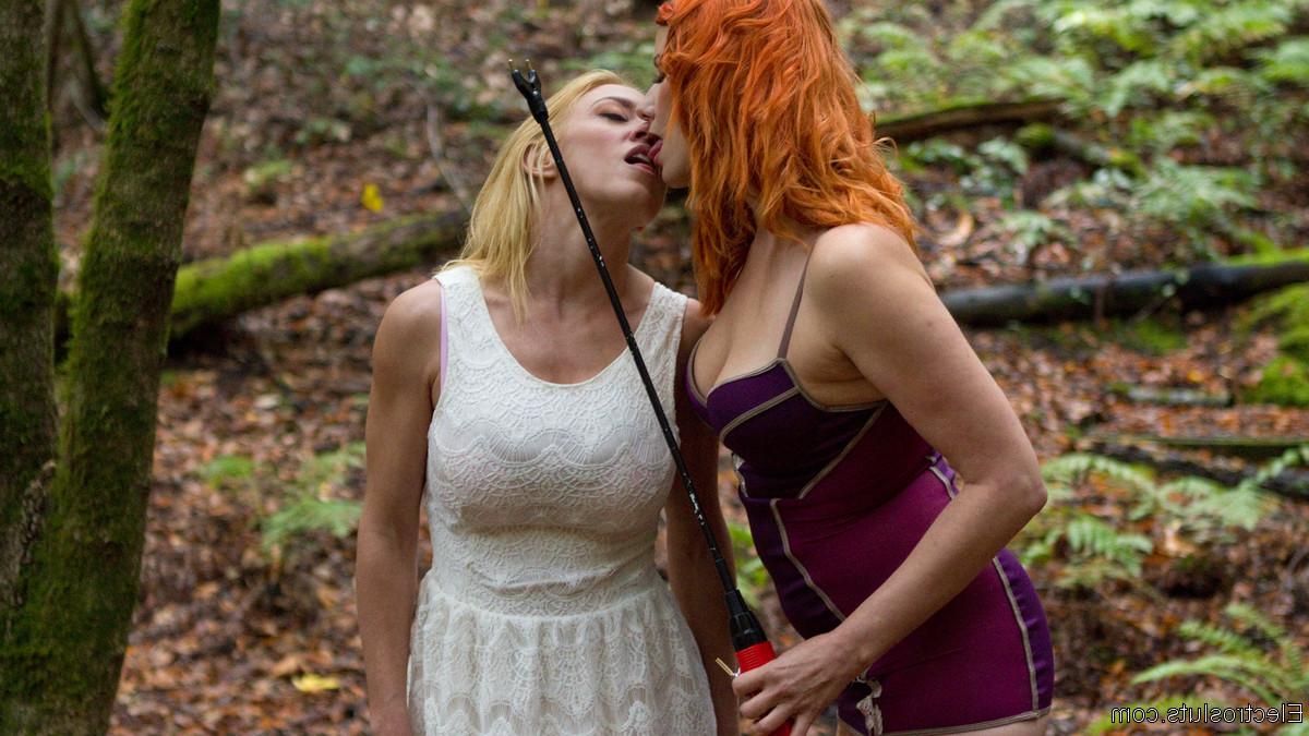 15P Une dominatrice rousse soumet la fille blonde Dee Williams à un aiguillon pour le bétail dans les bois.