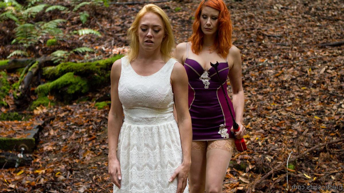 15P Une dominatrice rousse soumet la fille blonde Dee Williams à un aiguillon pour le bétail dans les bois.