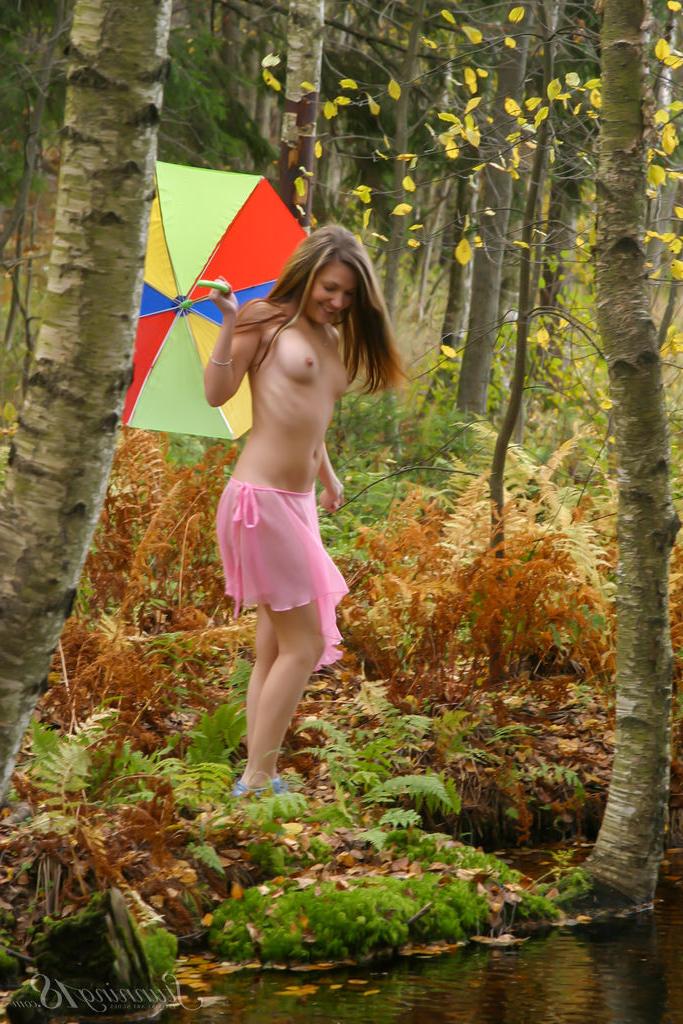 16P Kristina, de 18 anos, segura um guarda-chuva enquanto está nua perto da água