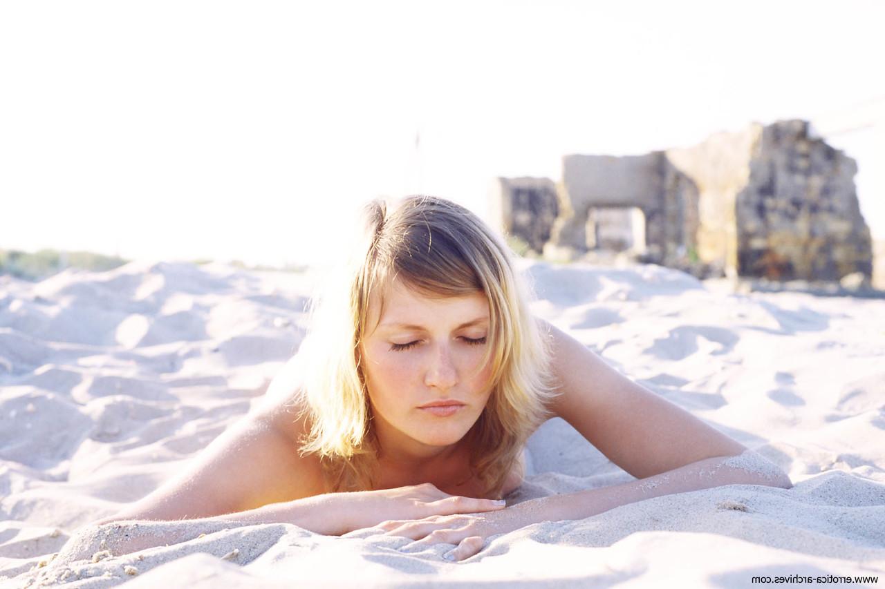 20P Lenna, jeune aux petits seins, pose nue sur la plage de sable.