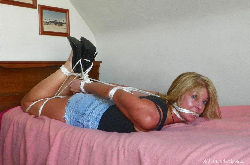 15P Clothed female is gagged while tied up with rope on a single bed