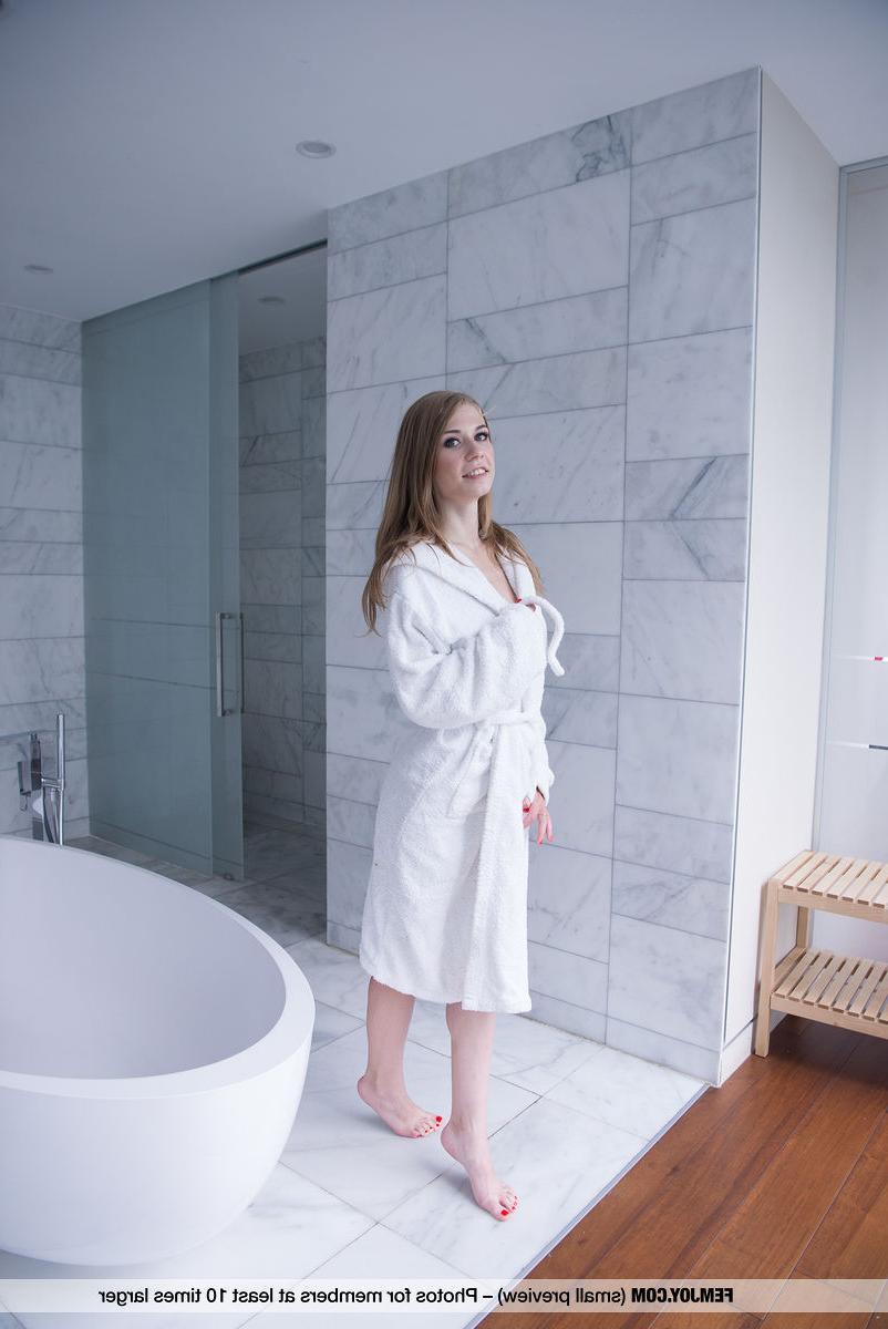 16P La joven delgada eva gold se quita la bata de baño para posar desnuda en el baño