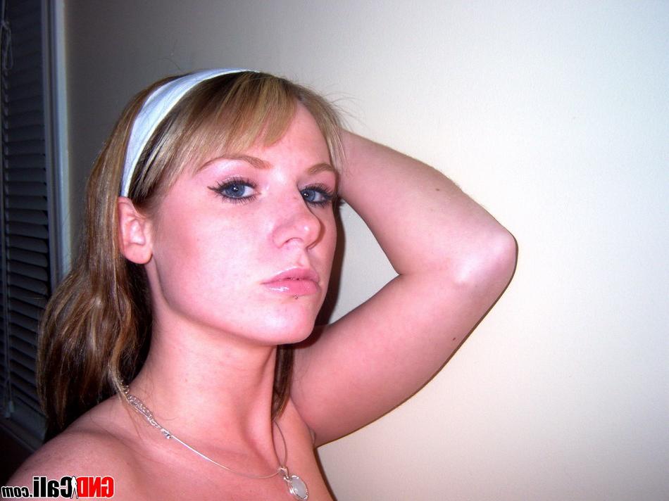 12P Blonder Teenager macht Selfies, während er oben ohne vor einem Spiegel steht