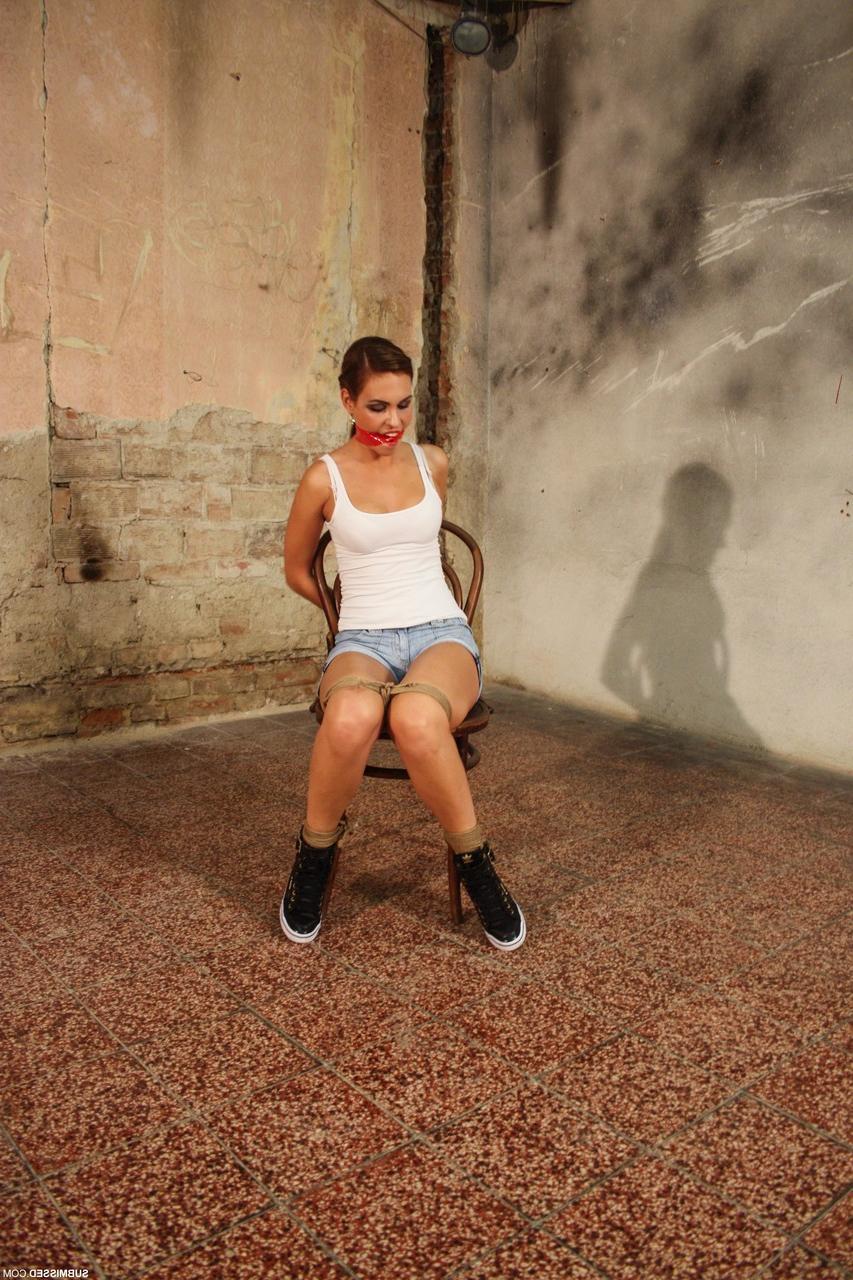 20P Wunderschöne Brünette posiert in Jeansshorts und einem weißen Tanktop an einen Stuhl gefesselt