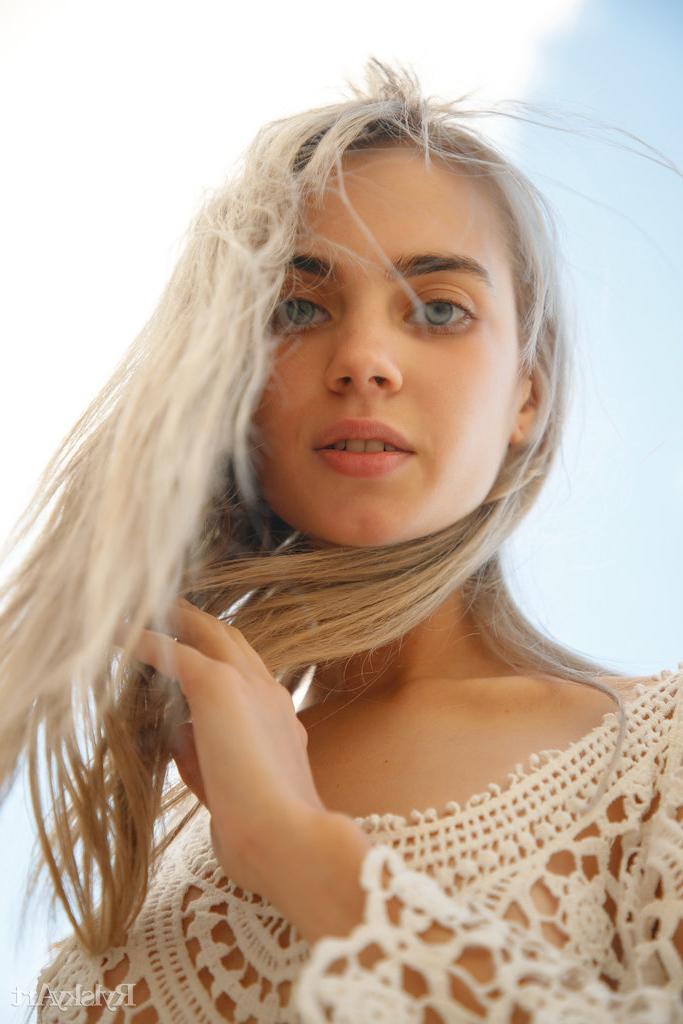 16P Sofy Bee, une jeune blonde platine, enlève sa robe en dentelle pour se mettre nue sur un sol rocailleux.