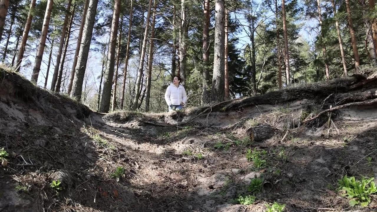 15P Brunette chick Katy Dee takes a badly needed pee over a bank in the woods