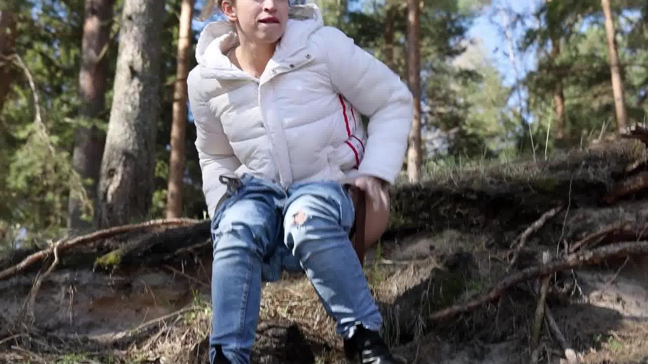 15P Brunette chick Katy Dee takes a badly needed pee over a bank in the woods