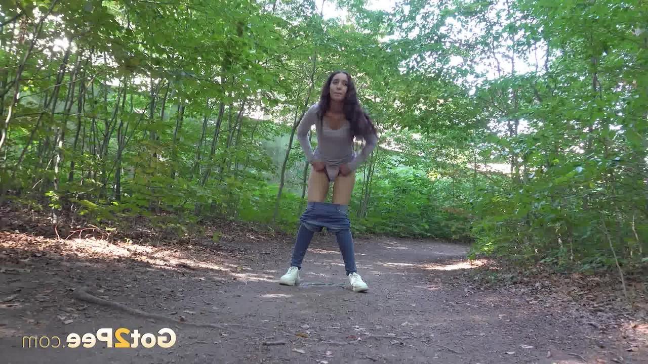 15P Pretty brunette Esperansa pulls down her jeans to take a pee in a forest
