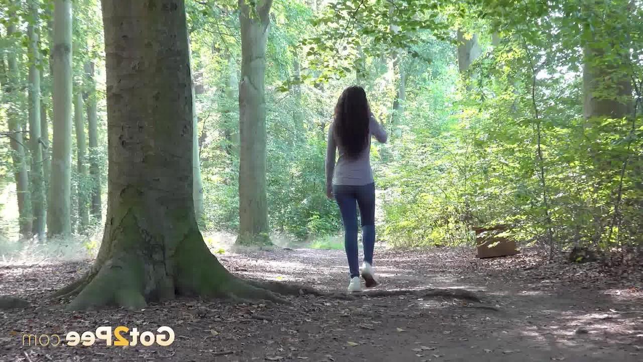 15P Pretty brunette Esperansa pulls down her jeans to take a pee in a forest
