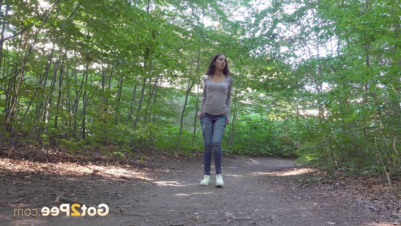 15P Pretty brunette Esperansa pulls down her jeans to take a pee in a forest