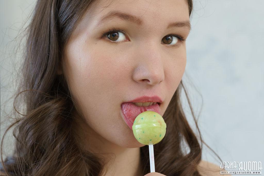 20P Young beauty Ariel licks a sucker while getting totally naked on a bed
