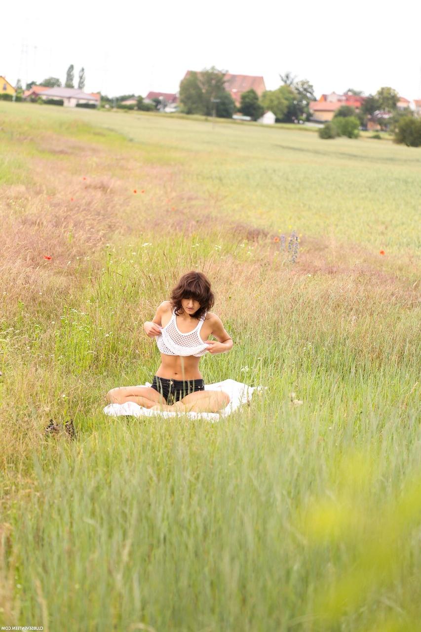 20P Suzy Rainbow, jeune brune et maigre, se déshabille et se masturbe dans la prairie.