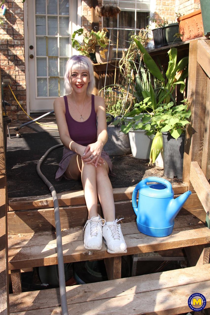 20P Sylvie J, blonde maigre en jupe, exhibe sa chatte dans un jardin intérieur.