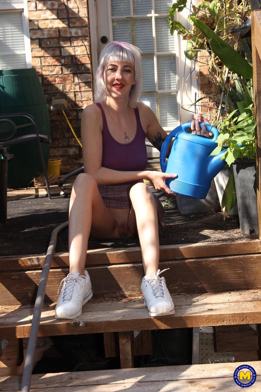 20P Sylvie J, blonde maigre en jupe, exhibe sa chatte dans un jardin intérieur.
