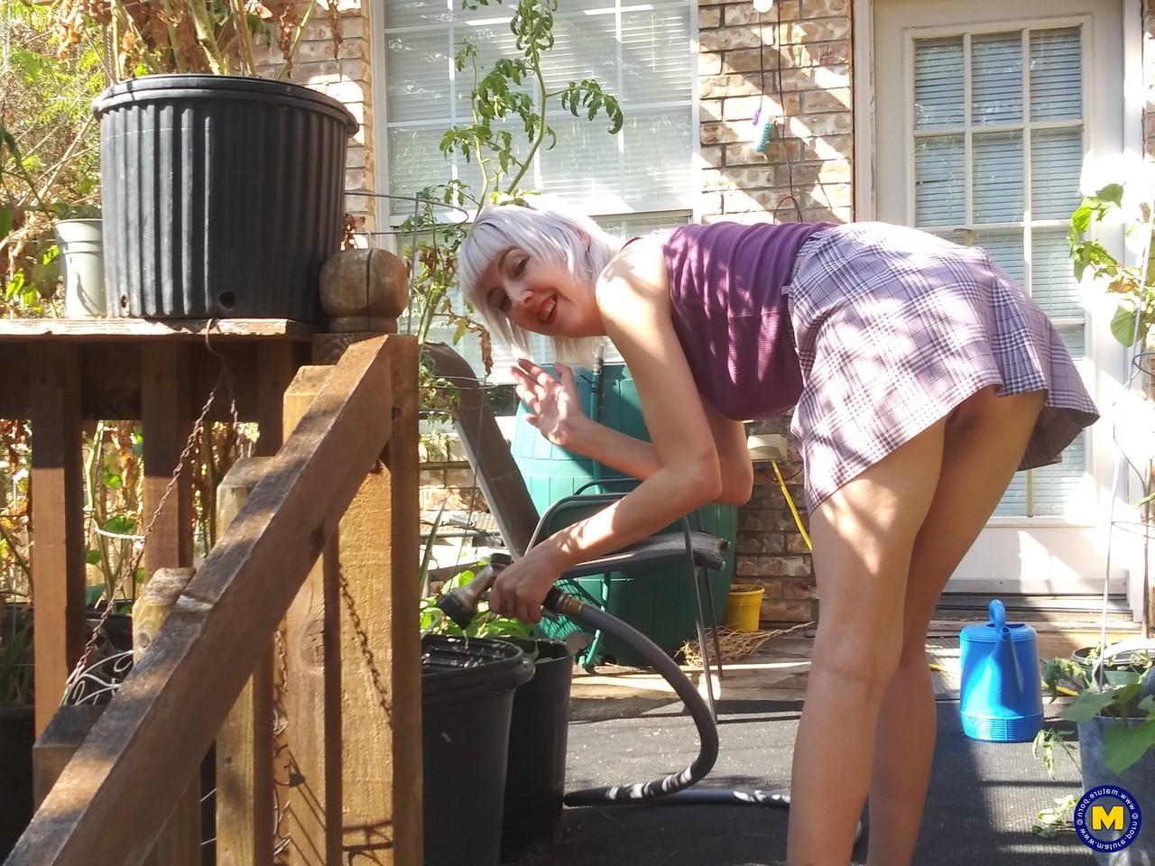 20P Sylvie J, blonde maigre en jupe, exhibe sa chatte dans un jardin intérieur.