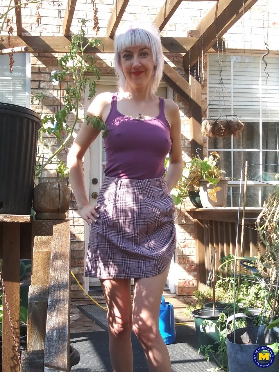 20P Sylvie J, blonde maigre en jupe, exhibe sa chatte dans un jardin intérieur.