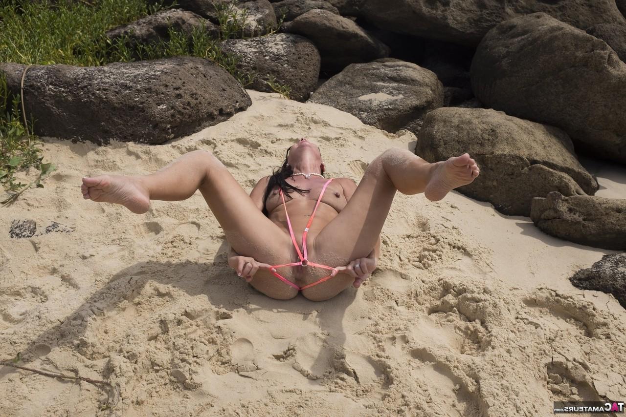 16P La MILF brune Roxeanne enlève son petit maillot de bain pour aller nue à la plage.